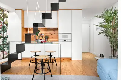 a kitchen and living room with white cabinets and stools at Jasmine Loft in Porto