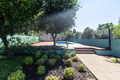 a garden with a pool and trees and a fence at Oporto Swimming Pool House in Porto