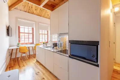 a kitchen with white cabinets and a tv at D&S - Falling Leaves in Porto