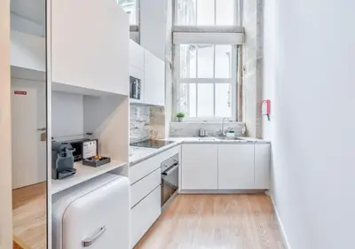 a kitchen with white cabinets and a window at Oporto Comfort Dom Hugo - Historic Apartments in Porto