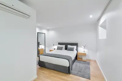 a white bedroom with a bed and a mirror at Oporto Comfort Dom Hugo - Historic Apartments in Porto