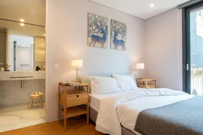a bedroom with a bed and a bathroom at LovelyStay - Primrose 2BR Flat with Free Parking, AC and Balcony in Porto