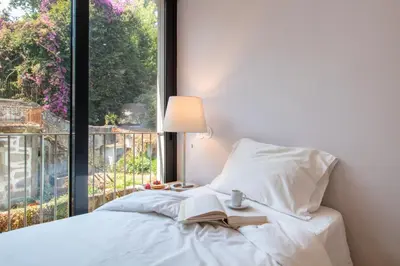 a bed with a book and a lamp and a window at LovelyStay - Primrose 2BR Flat with Free Parking, AC and Balcony in Porto