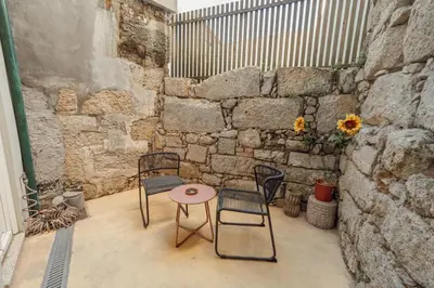 a patio with two chairs and a table and a wall at Cozy Flat with Terrace by Hosty in Porto
