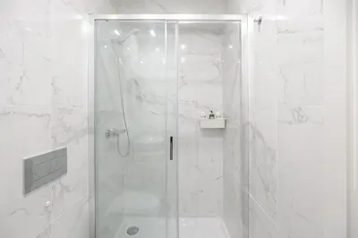 a white bathroom with a shower with a glass door at LovelyStay - Downtown Studio with Pool, AC and Balcony in Porto