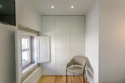 a white room with a chair and a window at LovelyStay - Downtown Studio with Pool, AC and Balcony in Porto