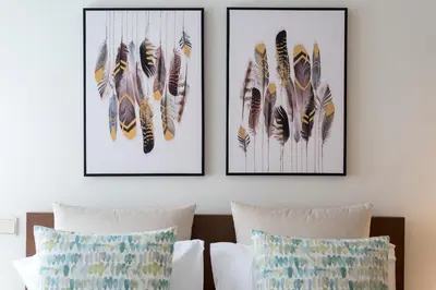 three framed prints of feathers on a wall above a bed at Rua de Camões in Porto