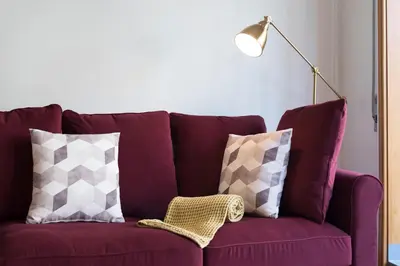 a purple couch with two pillows and a lamp at Rua de Camões in Porto