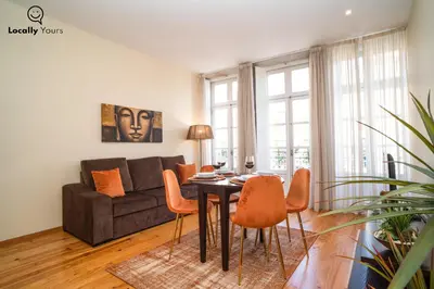 a living room with a table and chairs and a couch at Locally Yours Oporto Apartments in Porto