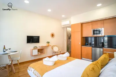 a bedroom with a large bed and a kitchen at Locally Yours Oporto Apartments in Porto