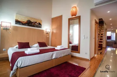a bedroom with a large bed and a mirror at Locally Yours Oporto Apartments in Porto