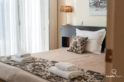 a bedroom with a bed with towels on it at Locally Yours Oporto Apartments in Porto