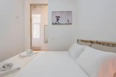 a white bed in a room with a picture on the wall at Rua do Freixo in Porto