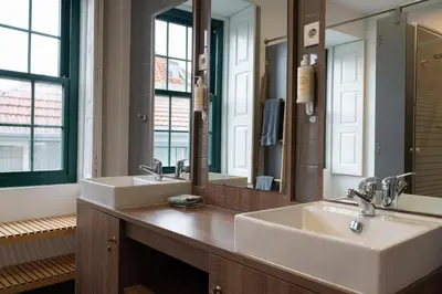 a bathroom with two sinks and two mirrors at Clerigos Townhouse Porto by PCH in Porto