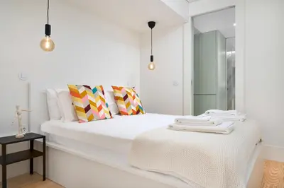 a white bedroom with a white bed and a mirror at Liiiving in Porto - Santa Catarina Boutique in Porto
