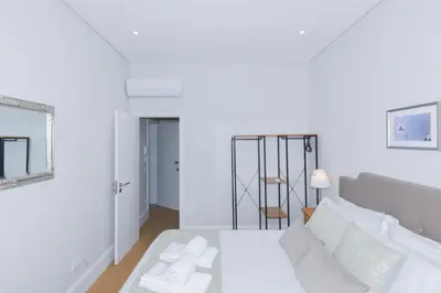 a white room with a bed and a mirror at Fontinha Square Apartments by Porto City Hosts in Porto