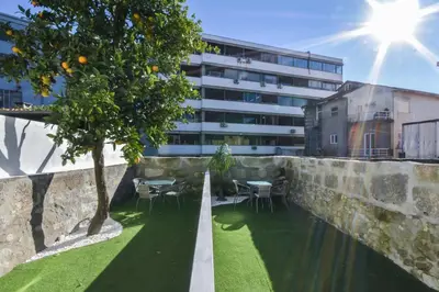 a retaining wall with an orange tree in front of a building at Fontinha Square Apartments by Porto City Hosts in Porto