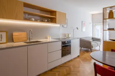 a kitchen with white cabinets and a table and a dining room at Cedofeita Studio 176 - Studio in city center in Porto