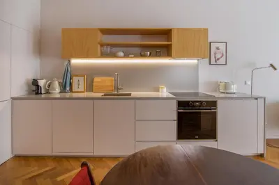 a kitchen with white cabinets and a wooden table at Cedofeita Studio 176 - Studio in city center in Porto