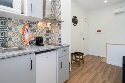 a kitchen with white cabinets and a wooden floor at OportoHost Dragão Duplex in Porto