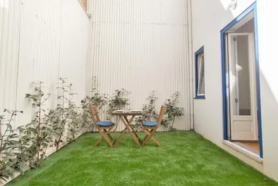 a patio with two chairs and a table on grass at Janelas de São Bento 3 by Porto City Hosts in Porto