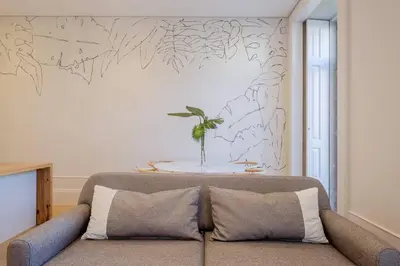 a couch sitting in a living room with a wall at BOUTIQUE Rentals- Art & Charm Apt w/ balcony & garage in Porto