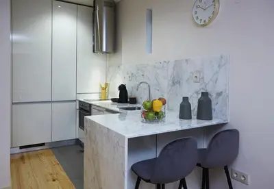 a kitchen with a counter with two chairs and a sink at ChillHouse_Porto - Praça da República in Porto