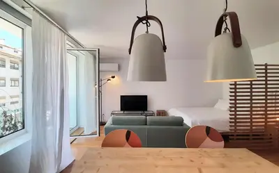 a living room with a green couch and two hanging lights at Nomad's Easy Stay - 1BED Porto Marquês in Porto