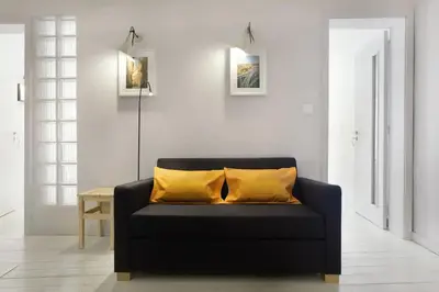 a living room with a black couch with yellow pillows at O´Porto Outeiro Flat in Porto