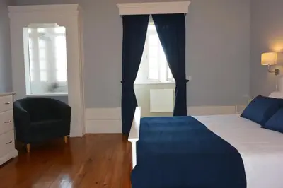a bedroom with a bed and a chair and two windows at Bonjardim 466 - Historic Townhouse in Porto