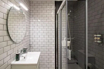 a white tiled bathroom with a sink and a shower at Alto da Lapa House w Parking by LovelyStay in Porto