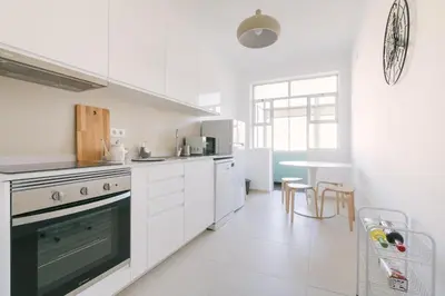 a white kitchen with white appliances and a table at D&S - Family Apartments I in Porto