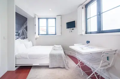 a white bedroom with a desk and a bed and windows at ON Apartments - Center in Porto
