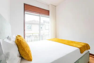 a bedroom with a large white bed with yellow pillows at Oporto Trindade Downtown in Porto