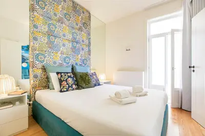 a bedroom with a large white bed with a colorful wall at Oporto Flores Plaza by LovelyStay in Porto