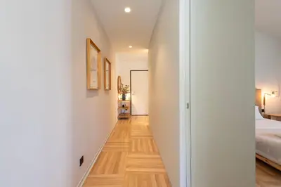 a hallway leading to a bedroom with white walls and wood floors at Prime Riverside in Porto