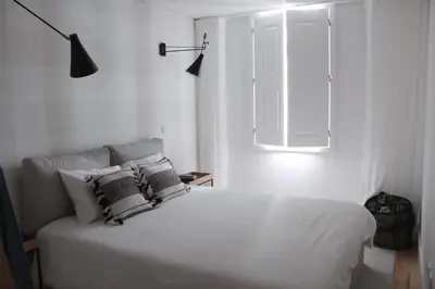 a white bedroom with a bed with pillows and a window at Oporto Garden's Home in Porto