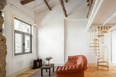 a living room with a leather chair and stairs at Uba - Heritage and Wine in Porto