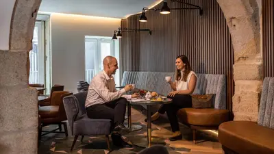 a man and woman sitting at a table in a restaurant at Pousada do Porto - Rua das Flores in Porto