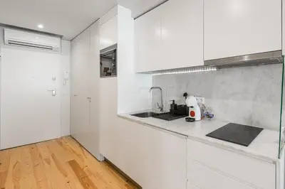 a white kitchen with white cabinets and a wooden floor at GuestReady - Private oasis for two in Porto