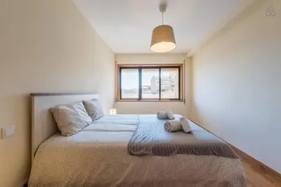 a bedroom with a large bed with two towels on it at Gaia House - Apartamento com Metro à Porta e Centro Histórico Perto in Vila Nova de Gaia