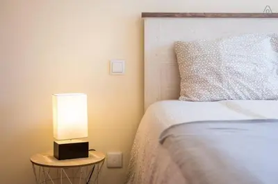 a bedroom with a bed and a lamp on a night stand at Gaia House - Apartamento com Metro à Porta e Centro Histórico Perto in Vila Nova de Gaia