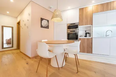 a kitchen with a wooden table and white chairs at Casa das Musas 2 in Porto