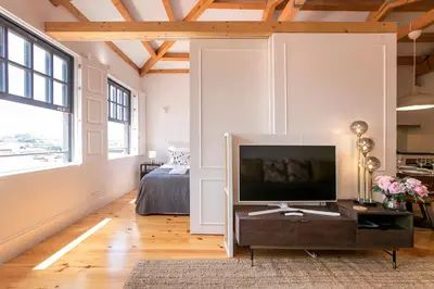 a living room with a television and a bed at Newly Renovated Cozy Central Loft w/ AC by LovelyStay in Porto