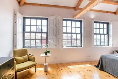a bedroom with windows and a bed and a chair at Newly Renovated Cozy Central Loft w/ AC by LovelyStay in Porto