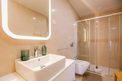 a bathroom with a sink and a toilet and a mirror at Newly Renovated Cozy Central Loft w/ AC by LovelyStay in Porto