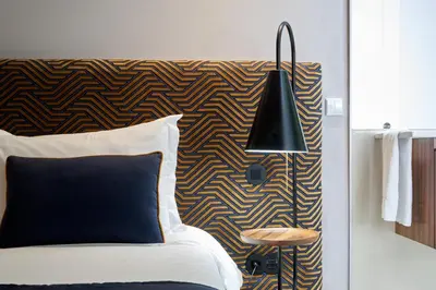 a bedroom with a bed with a black lamp and a wall at Rio da Vila in Porto