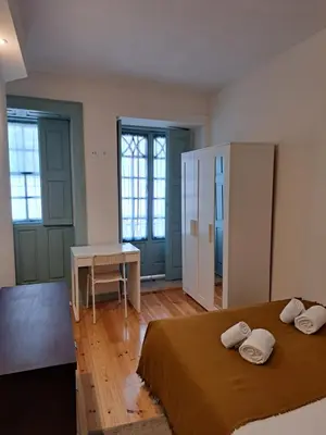a bedroom with a bed and a desk and windows at Near River 63 in Vila Nova de Gaia