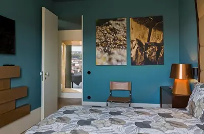 a bedroom with a blue wall with a bed and a chair at Infante Douro View in Porto
