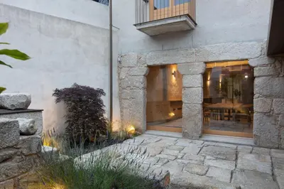 a house with a stone facade with a patio at Na Travessa Suítes in Porto